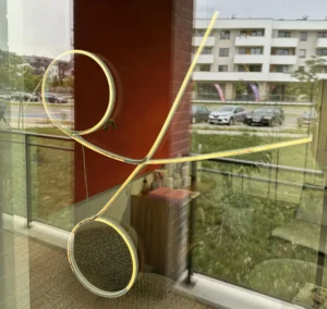Zżółknięty i wygięty neon LED w kształcie nożyczek — efekt działania promieni UV na nieodporne materiały.