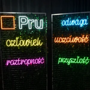 Neony LED z napisami na ściance eventowej dla firmy PRU — kolorowe napisy na tle zieleni, realizacja Ledeon