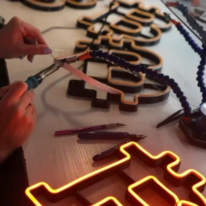 Ręczna produkcja neonu LED w warsztacie Ledeon — lutowanie elementów na stole produkcyjnym